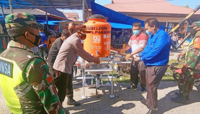 Kapolsek Bukit Batu Berkeliling di Kawasan Pasar Baru saat Bantu HKBP Bagikan Masker